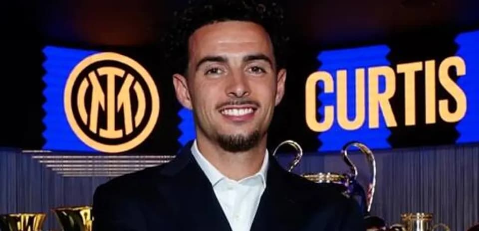 Player posing with trophies and club logo backdrop
