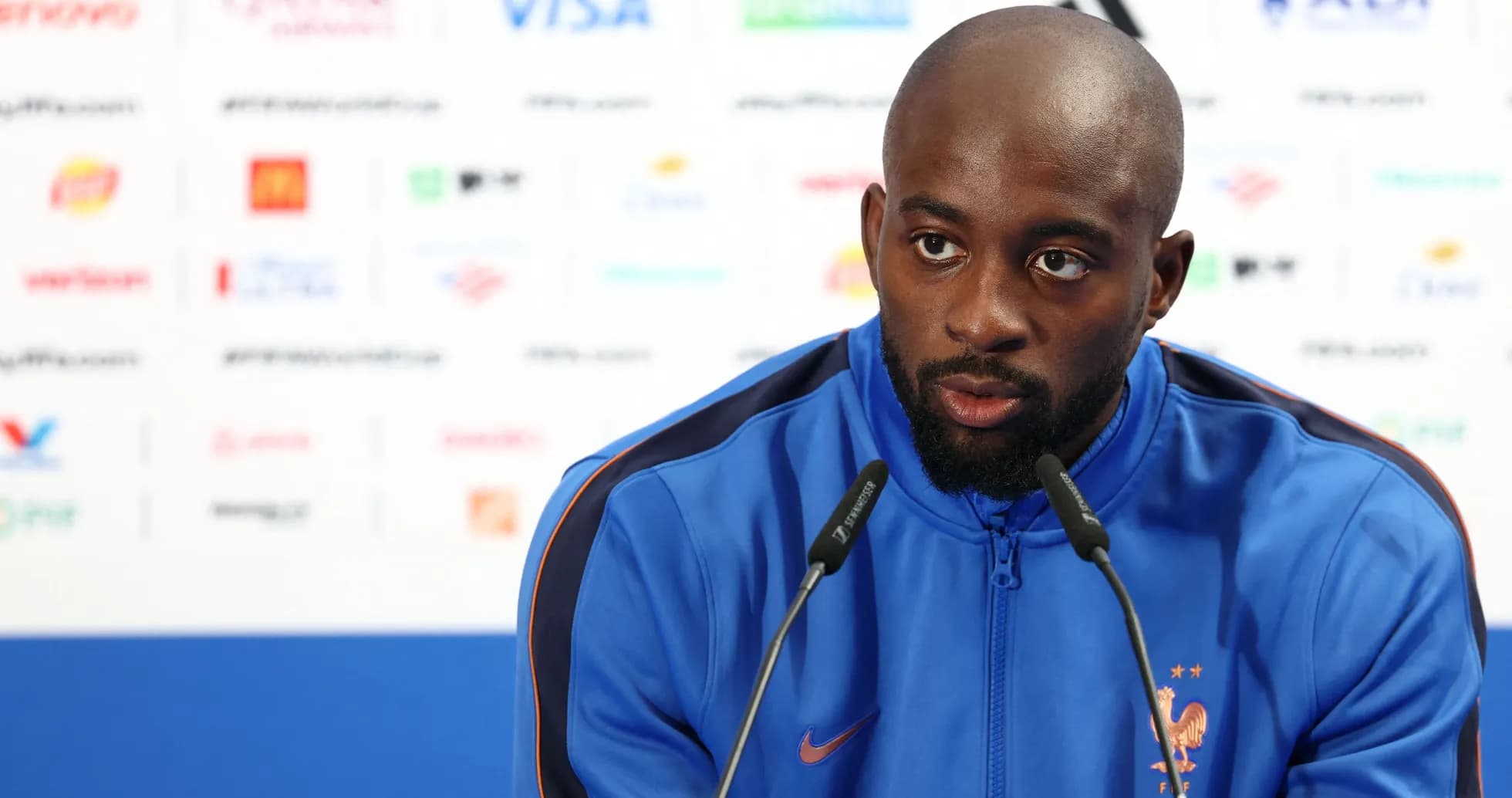 Player speaking at press conference with microphones