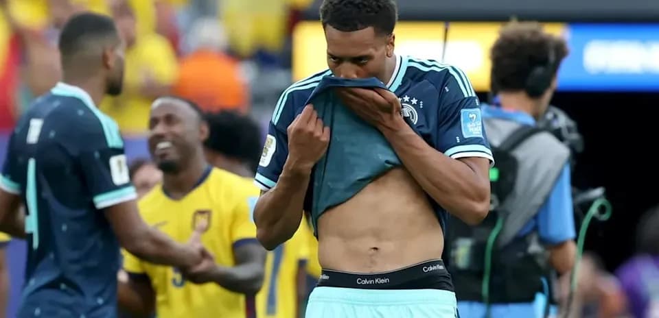 Player removing shirt after match, teammates celebrating