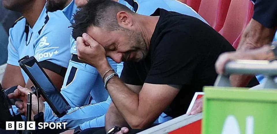 Coach sitting on bench, holding head in frustration