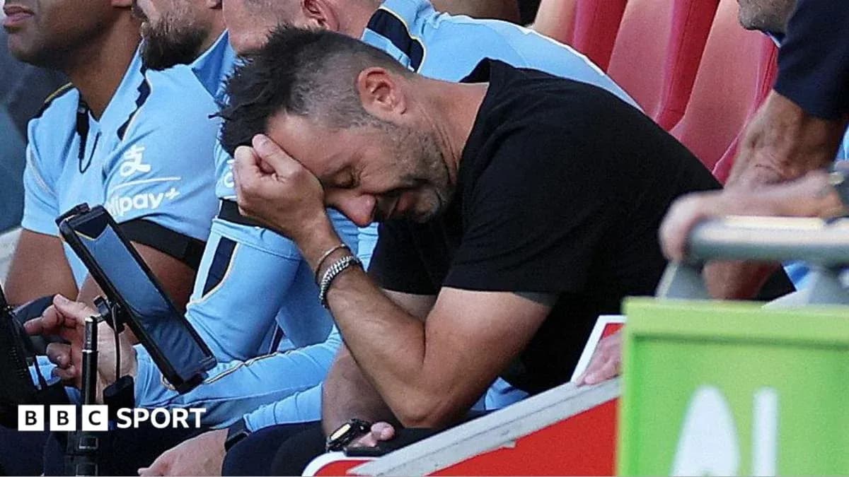 Coach sitting on bench, holding head in frustration