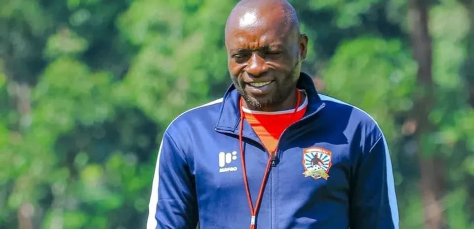 Coach walking on training ground with team logo