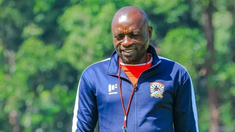 Coach walking on training ground with team logo