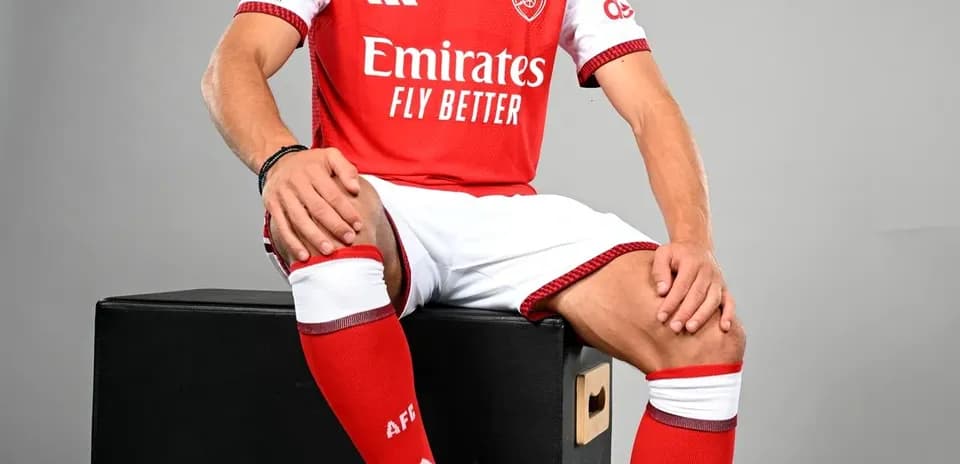 Player in Arsenal kit posing with a football