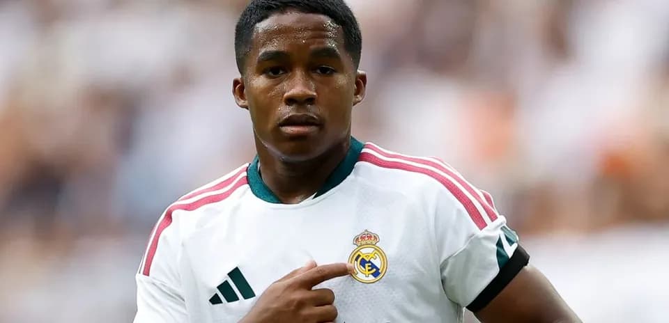 Player pointing at Real Madrid badge on jersey