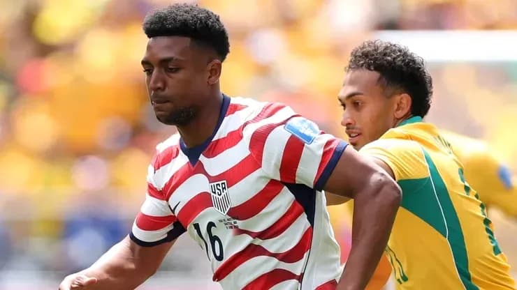 Player in striped USA jersey dribbling past opponent