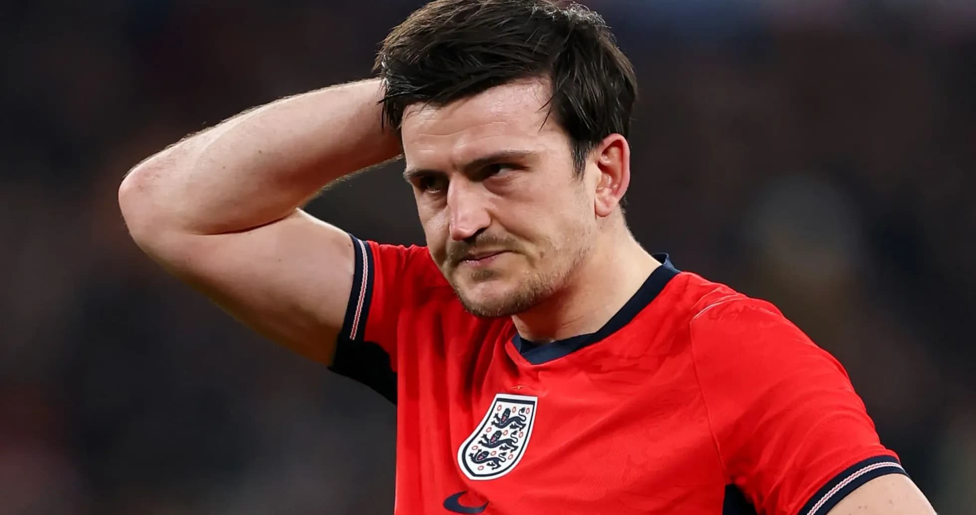 Player in red jersey with England crest, looking concerned