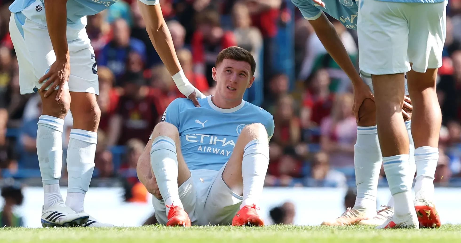 Player sitting on pitch with teammates assisting