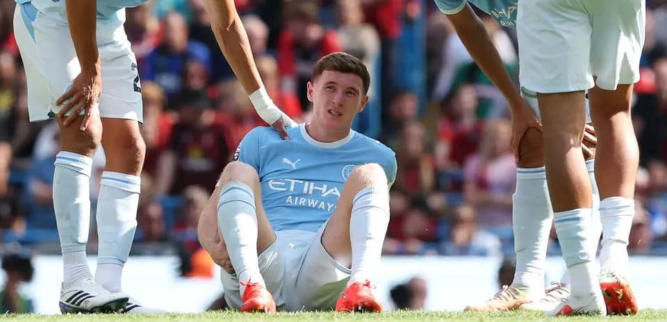Player sitting on pitch with teammates assisting