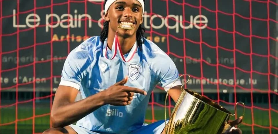 Player celebrating with trophy in front of goal net