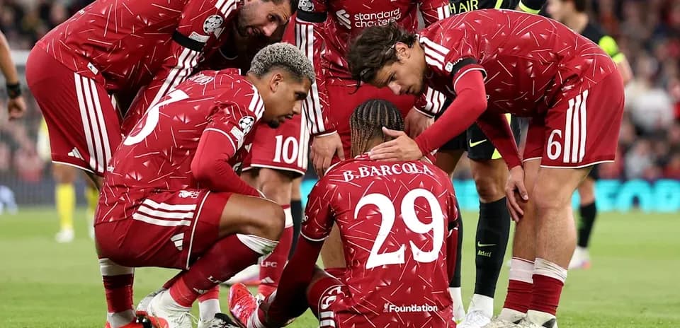 Liverpool players supporting teammate on the pitch