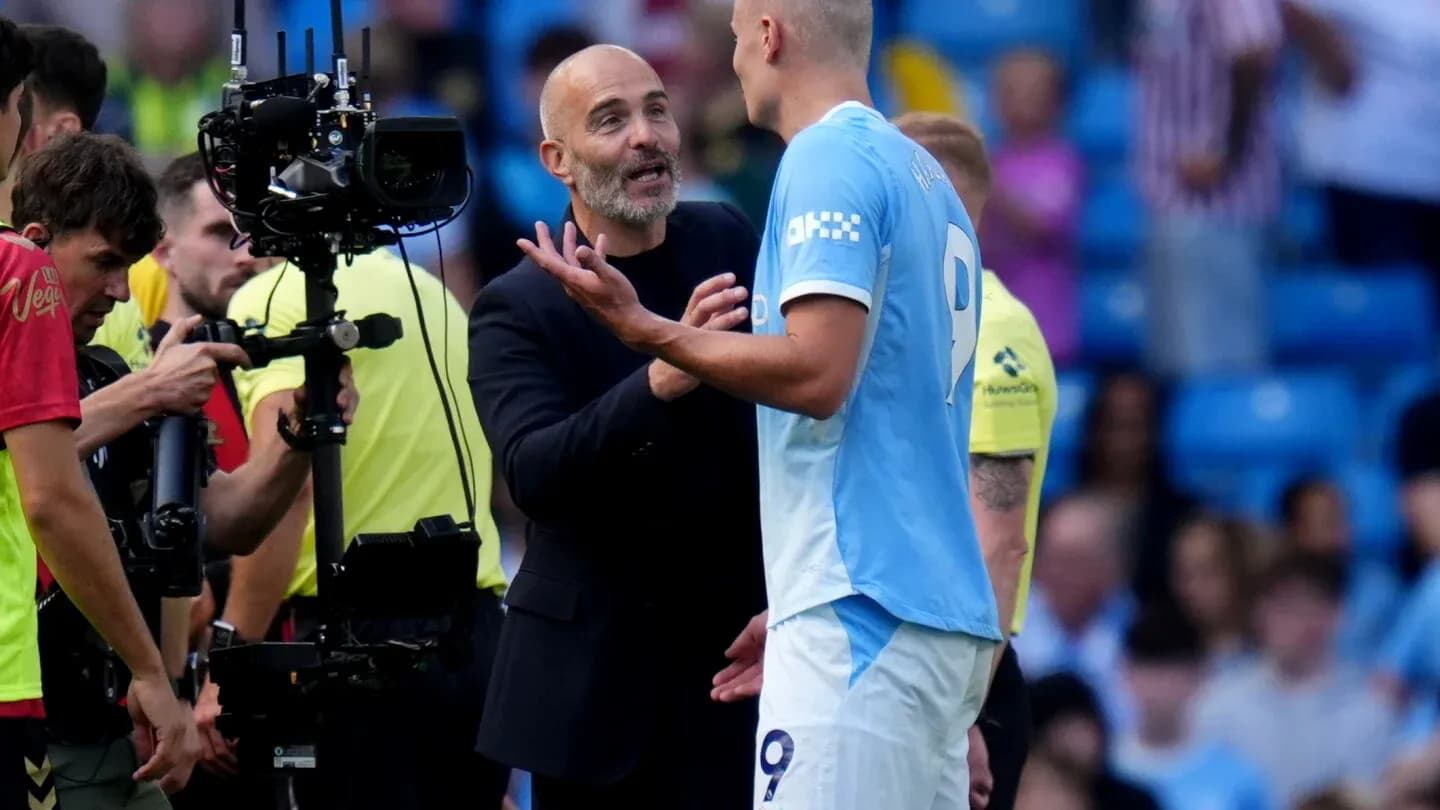 Manager discussing strategy with player on pitch