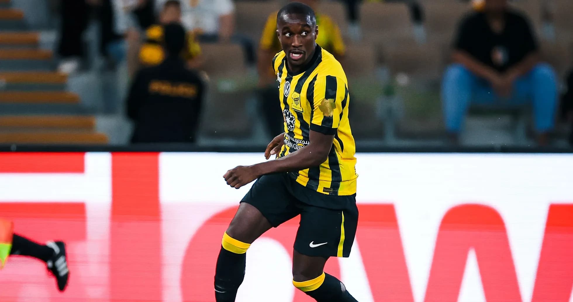 Player in yellow and black kit dribbling ball