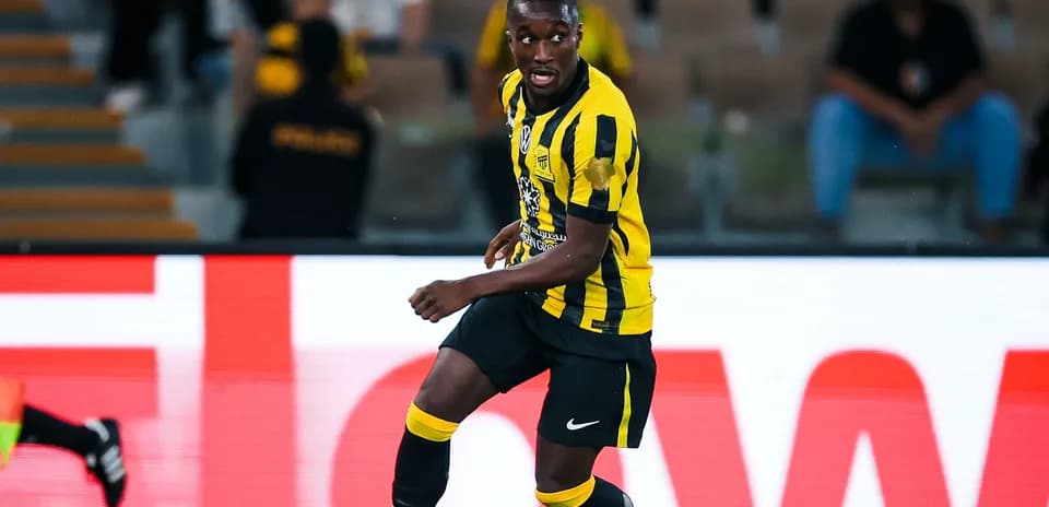Player in yellow and black kit dribbling ball