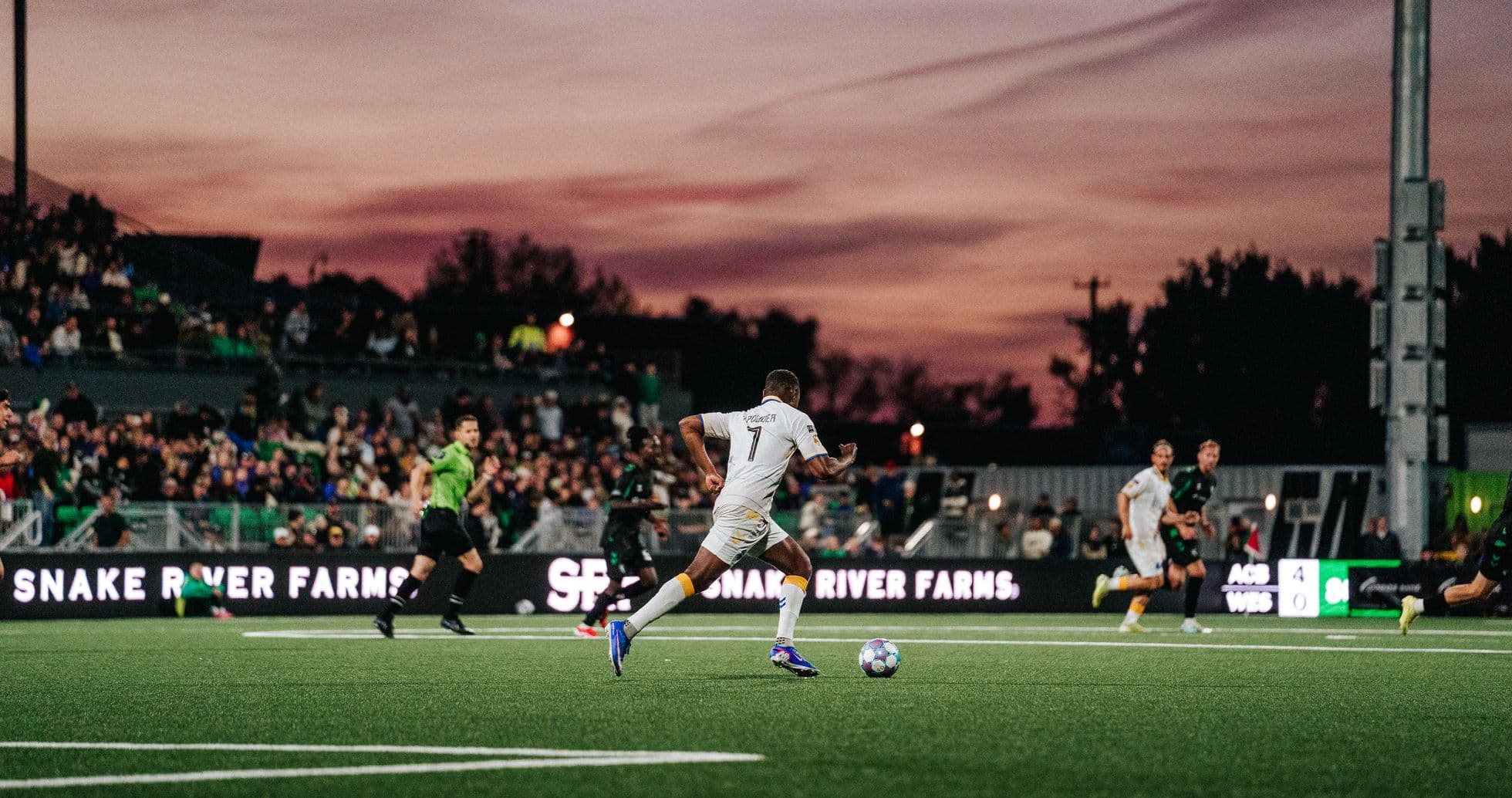 Player in white running with soccer ball during match