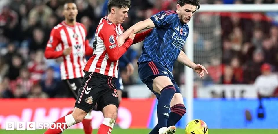 Sunderland player challenging Arsenal player for the ball