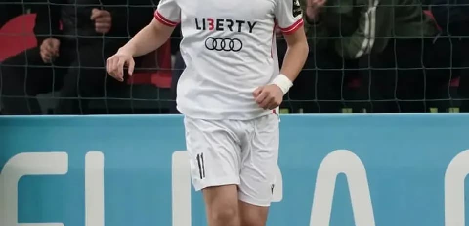 Player in white kit dribbling a soccer ball