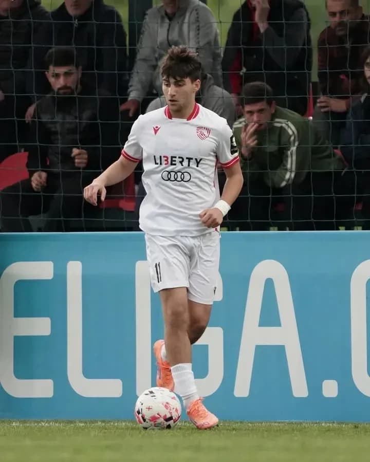 Player in white kit dribbling a soccer ball