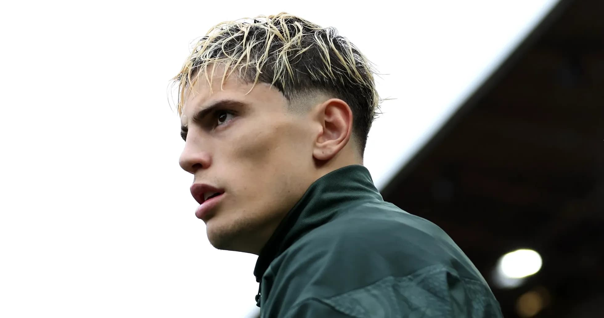 Player in green jacket looking away from camera