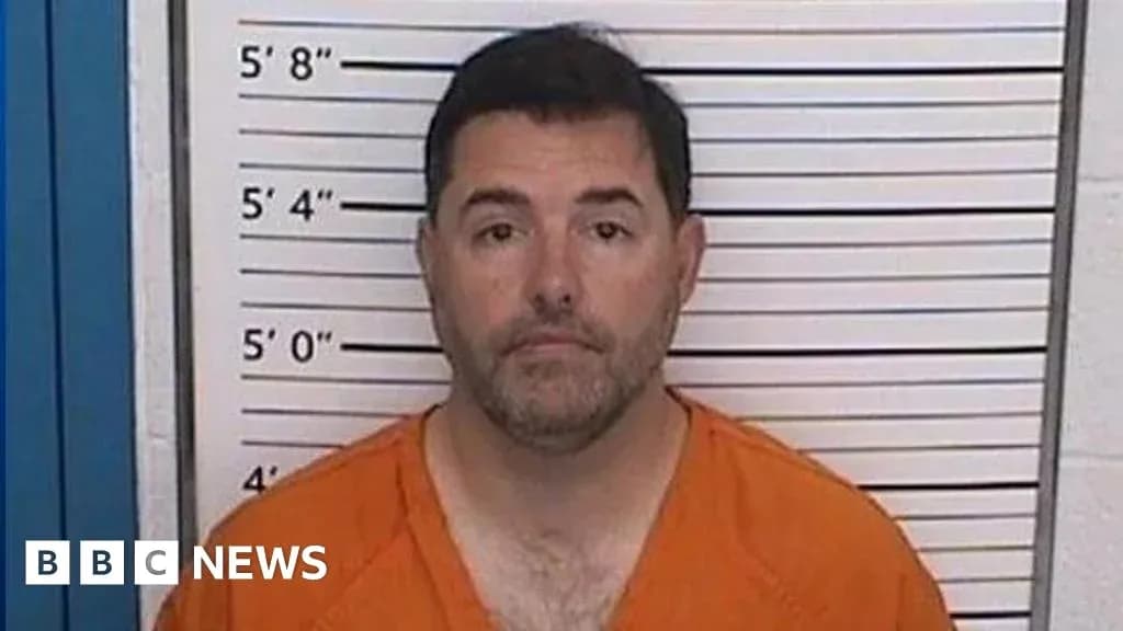 Man in orange jumpsuit at police booking station