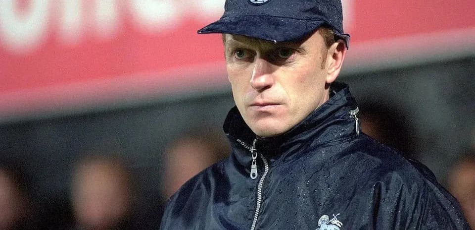 Coach observing match in rain at stadium