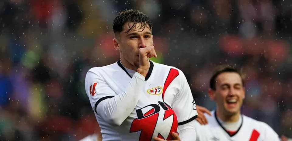 Player celebrating goal with teammates in rain