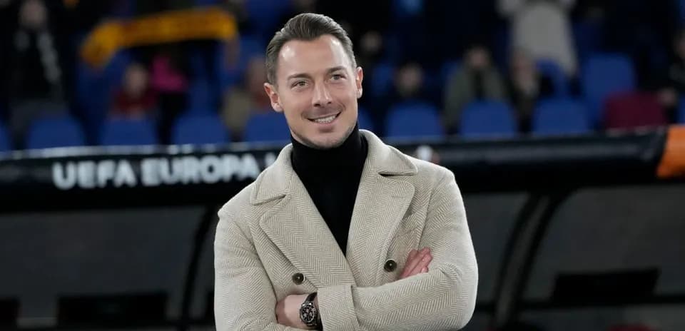 Man in stylish coat smiling at stadium