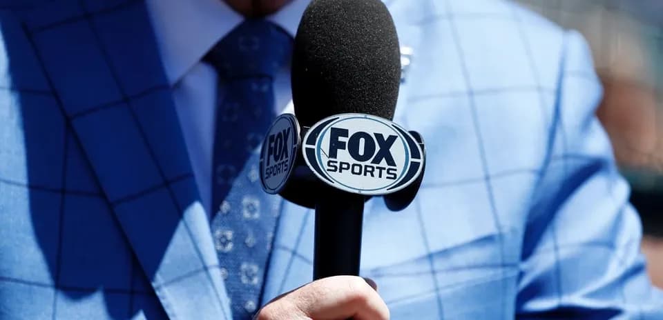 Person holding a FOX Sports microphone in suit