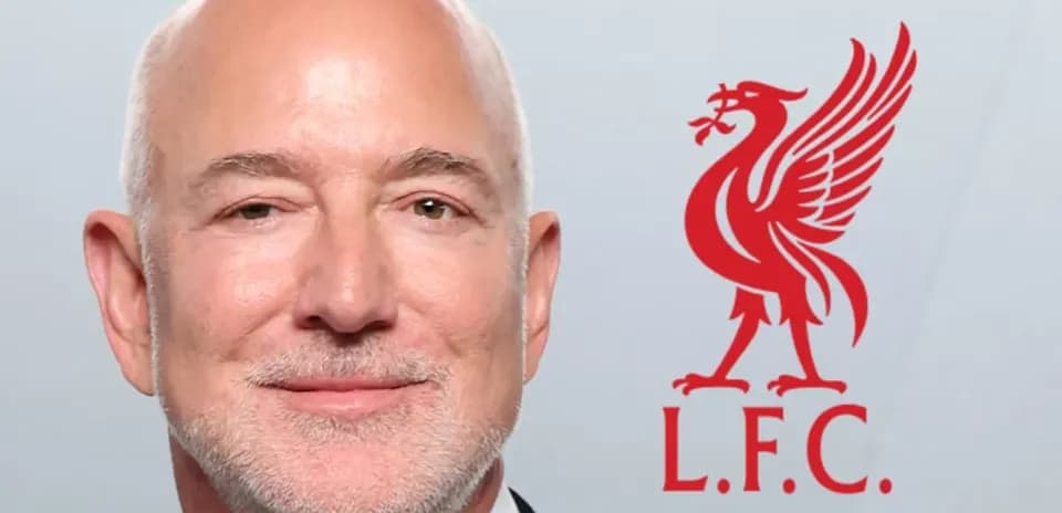 Man in tuxedo with Liverpool FC logo in background