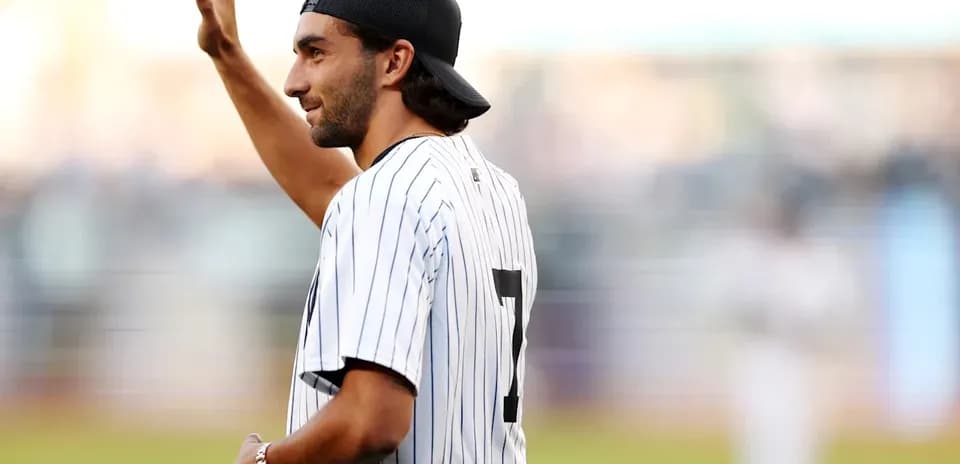 Person waving while wearing a baseball jersey