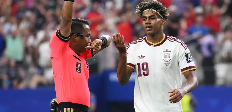 Referee issuing a card to Spanish player