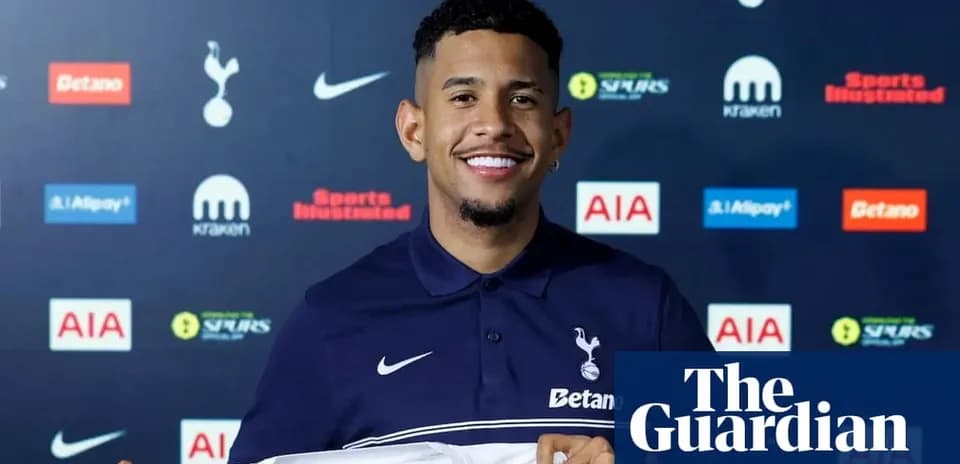 Player holding Tottenham jersey at press conference