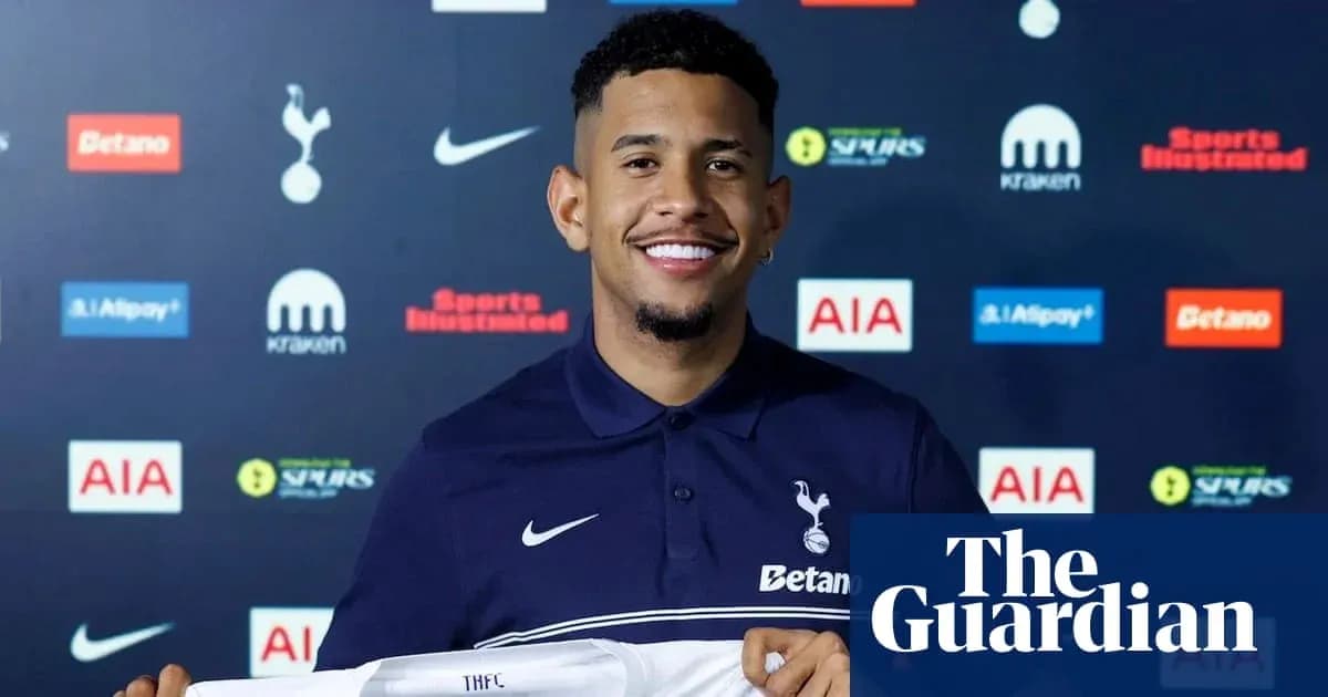 Player holding Tottenham jersey at press conference