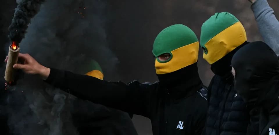Masked individuals holding a flare in smoky environment