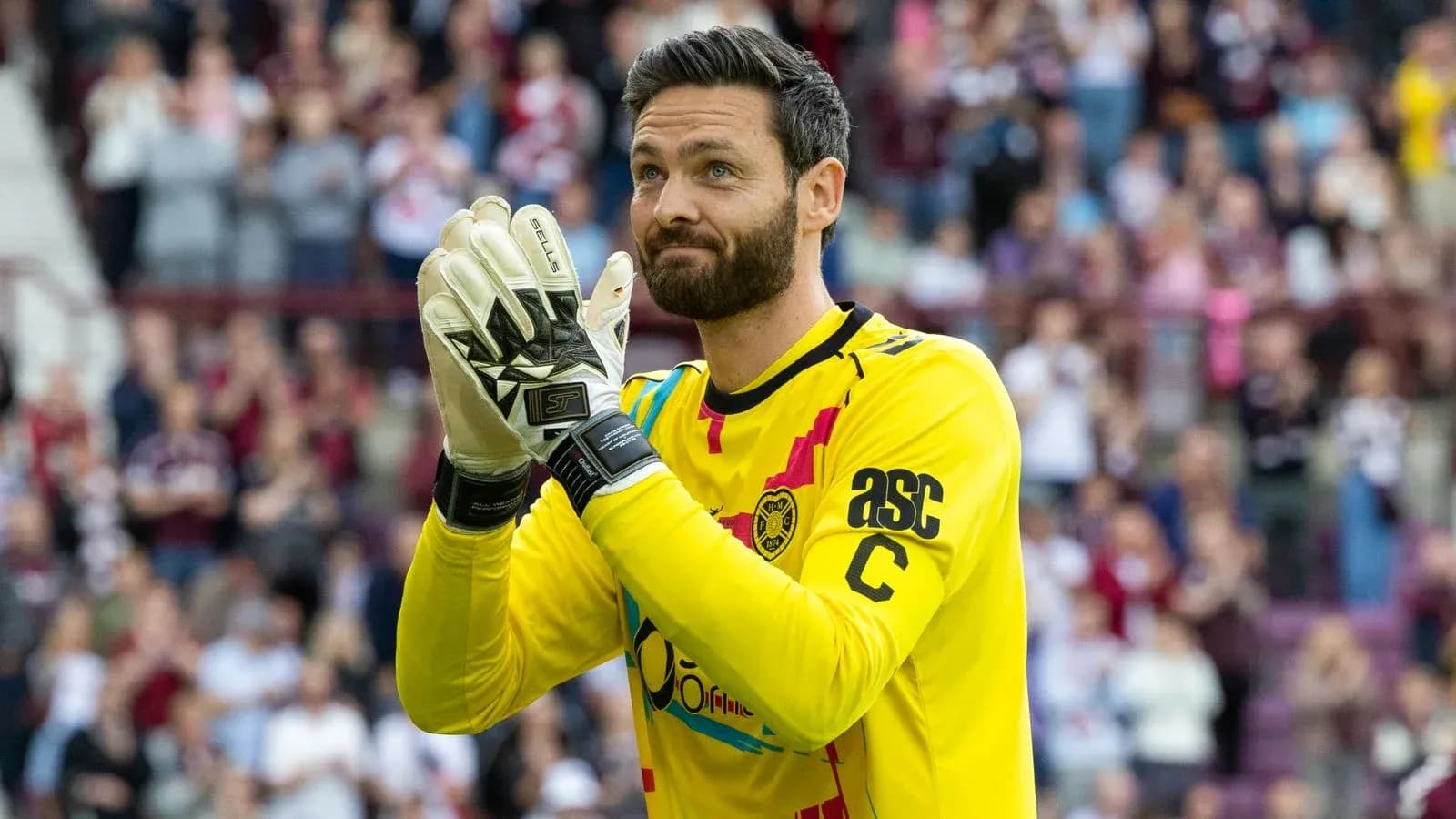 Goalkeeper applauding fans in yellow kit