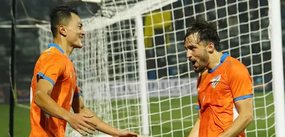 Two players celebrating a goal near the goalpost