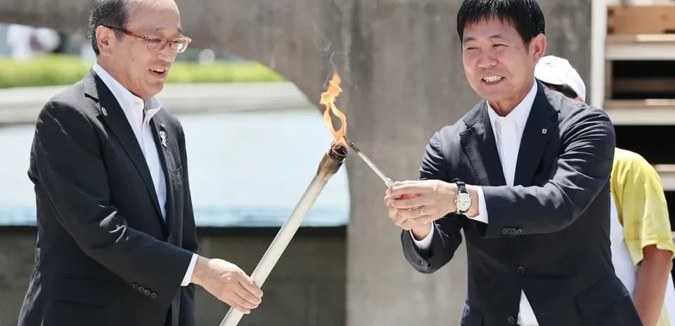 Two officials lighting a torch together outdoors