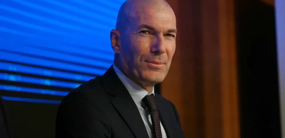 Man in suit seated at press conference table