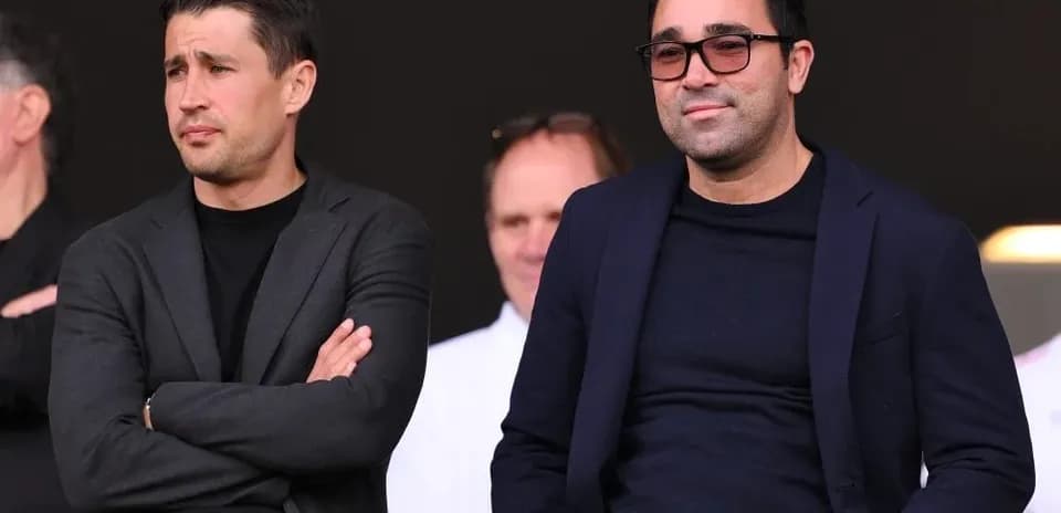 Two men seated in a stadium observing the match