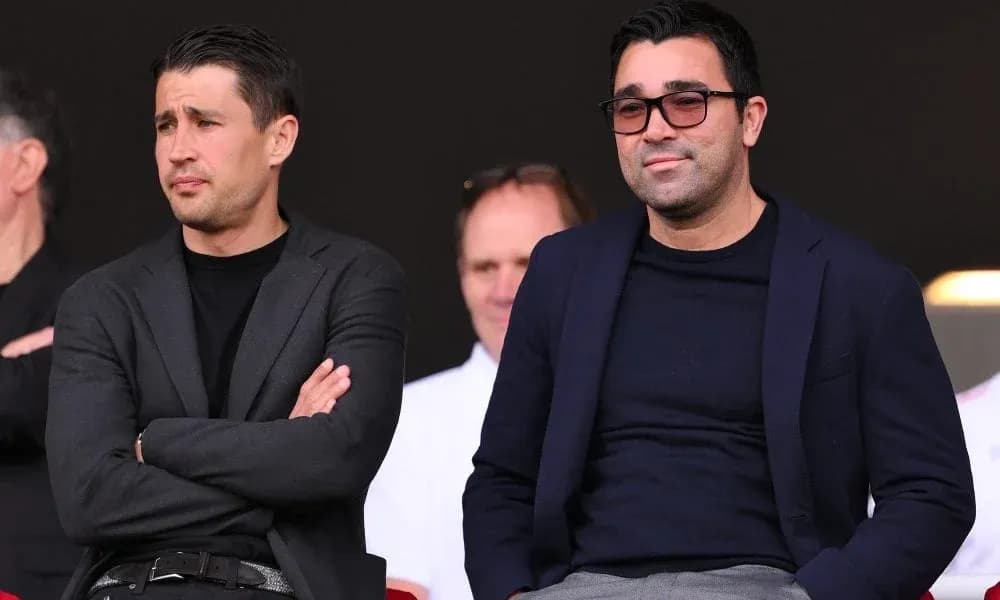 Two men seated in a stadium observing the match