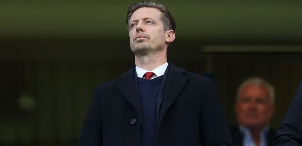 Man in black coat observing from the stands