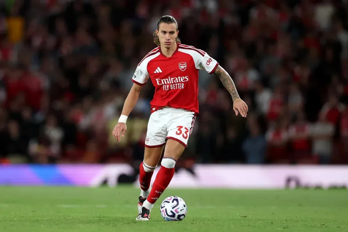 Player in Arsenal kit dribbling ball on pitch