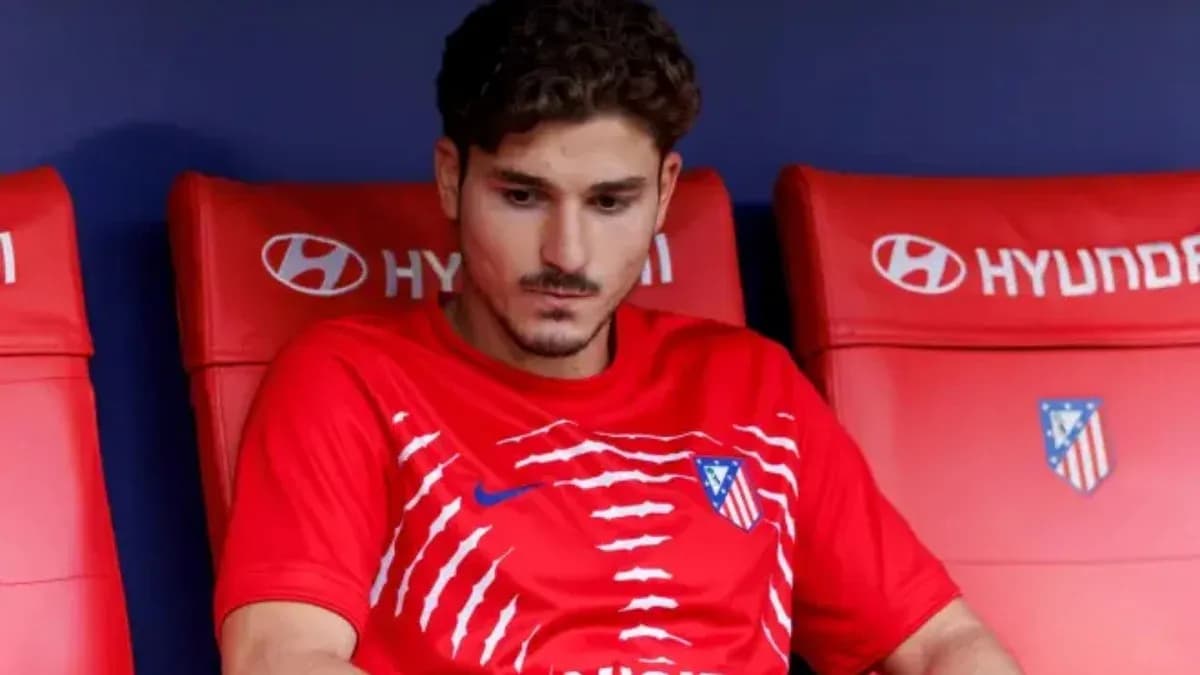 Player sitting on bench wearing Atletico Madrid jersey