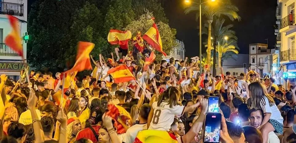 Crowd celebrating with Spanish flags at night