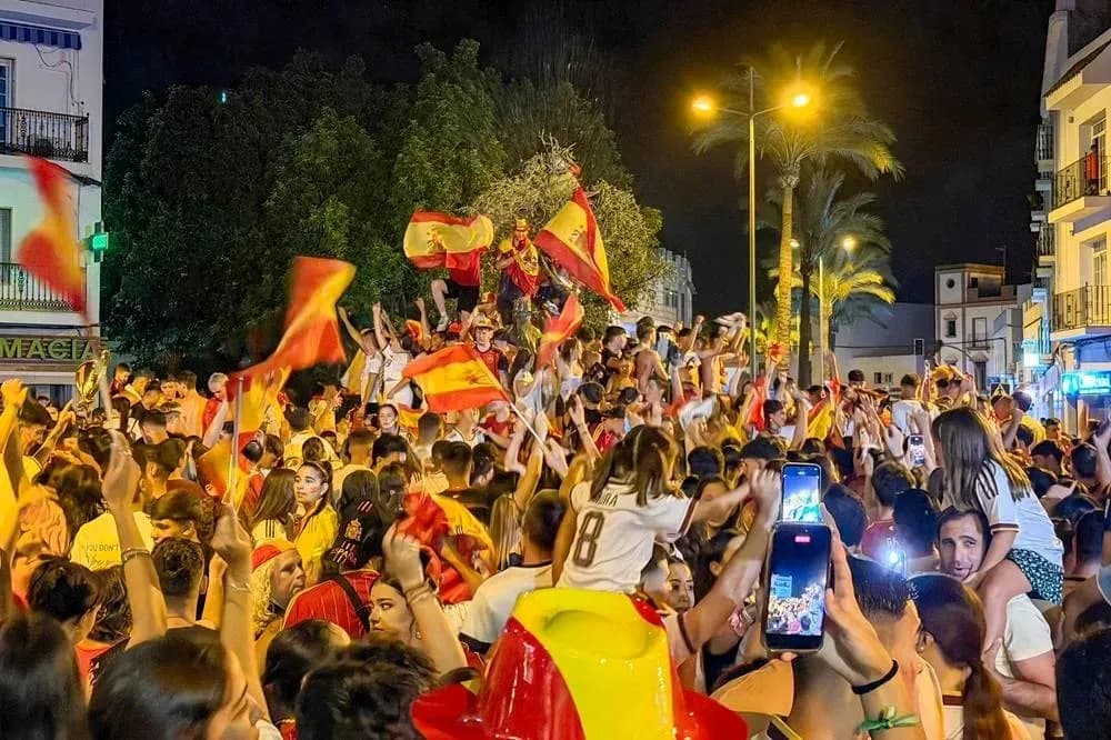 Crowd celebrating with Spanish flags at night