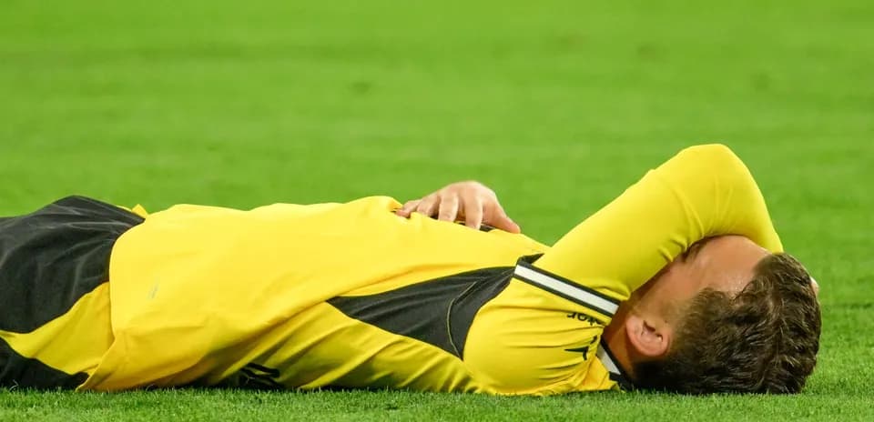 Player lying on field with hands over face