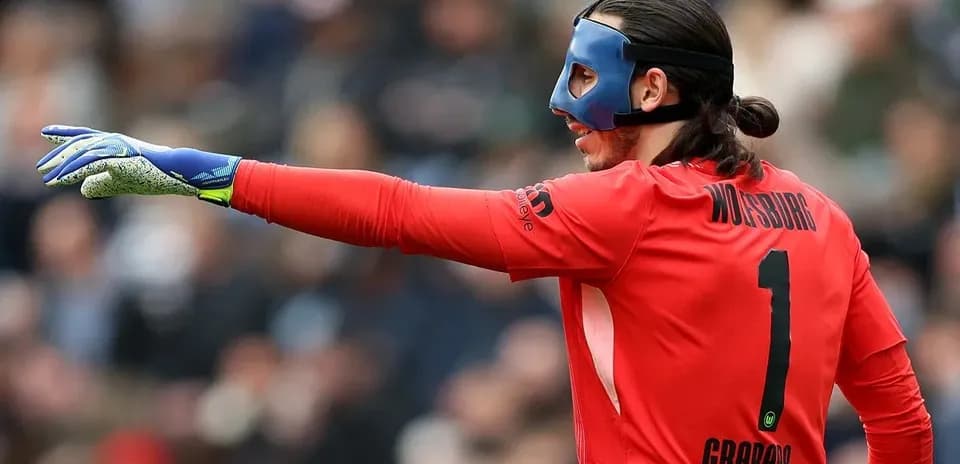 Goalkeeper in red uniform signaling during match