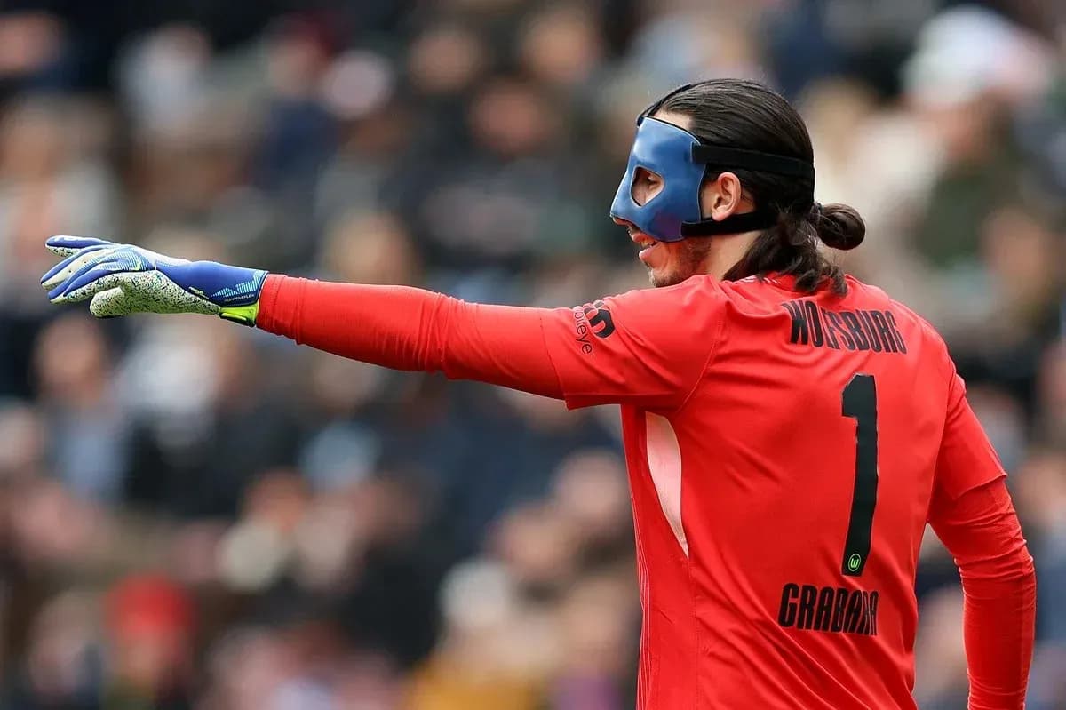 Goalkeeper in red uniform signaling during match