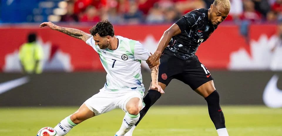 Two soccer players battling for the ball on field