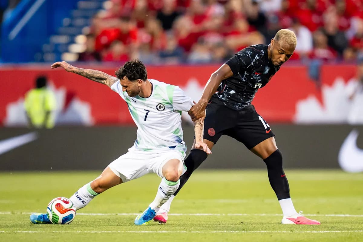 Two soccer players battling for the ball on field